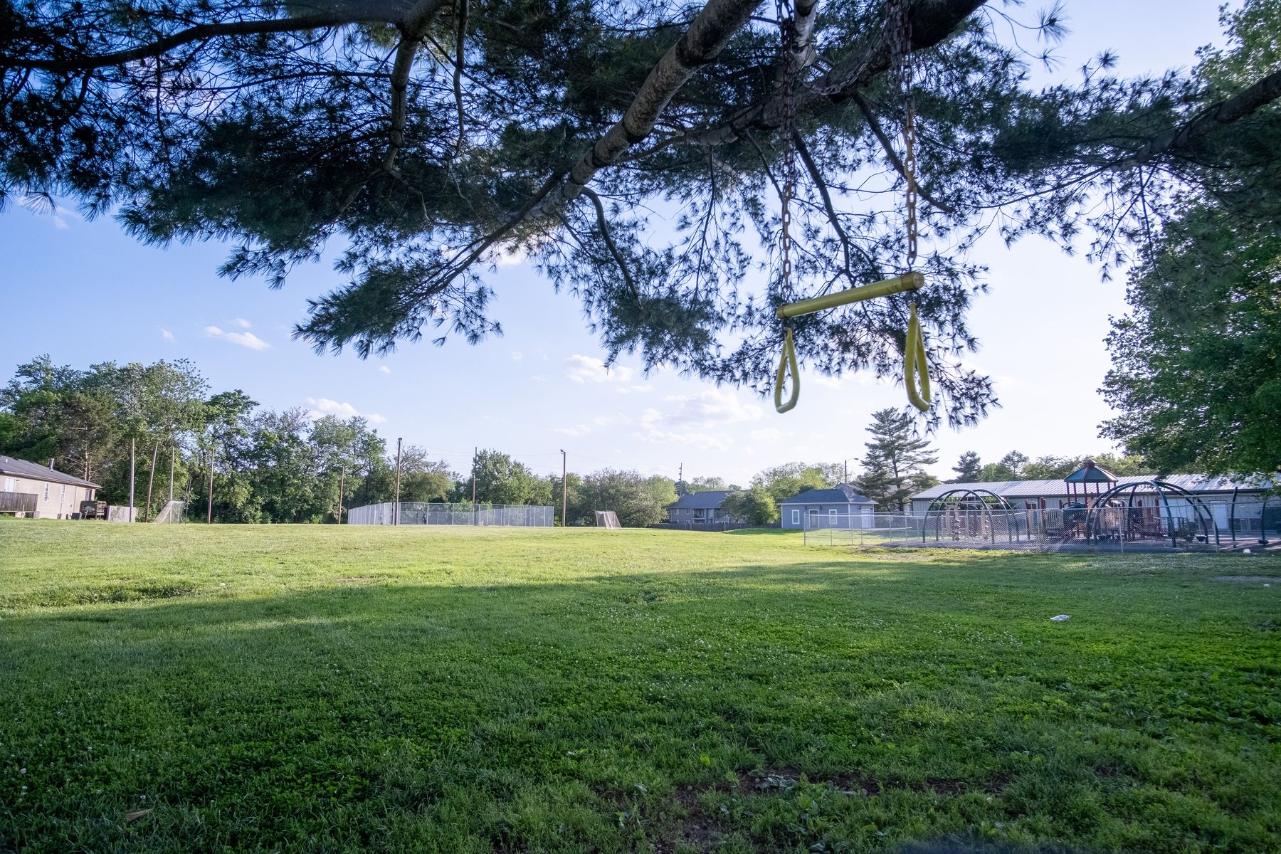 The open field, fenced basketball court and playground on the Guiding Light campus